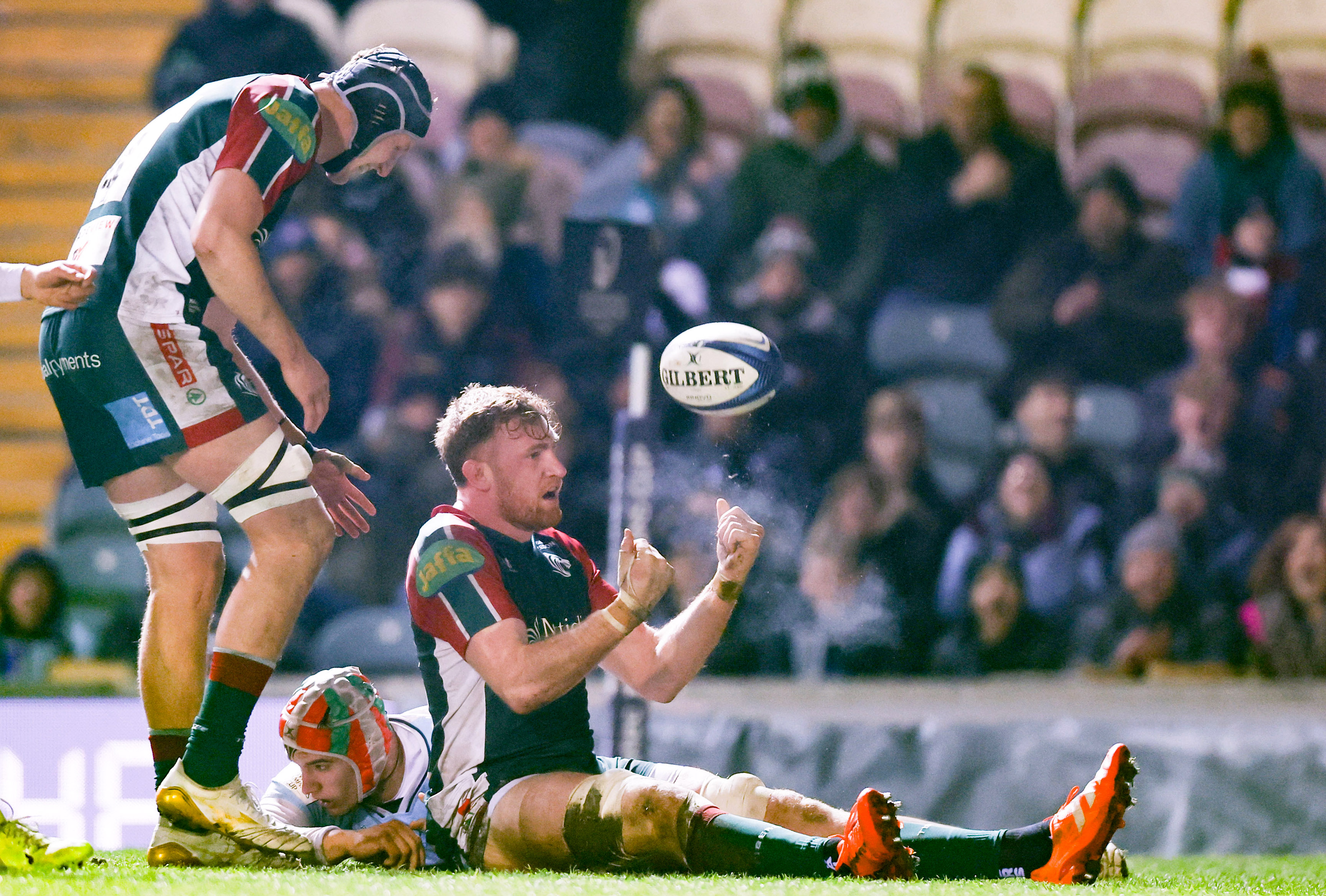 Ollie Chessum celebrates scoring a try while a teammate stands over an opponent on the ground.