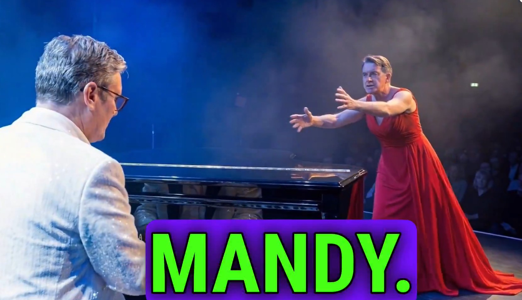 A man in a white suit playing piano faces another man in a red dress with outstretched arms, as if singing.