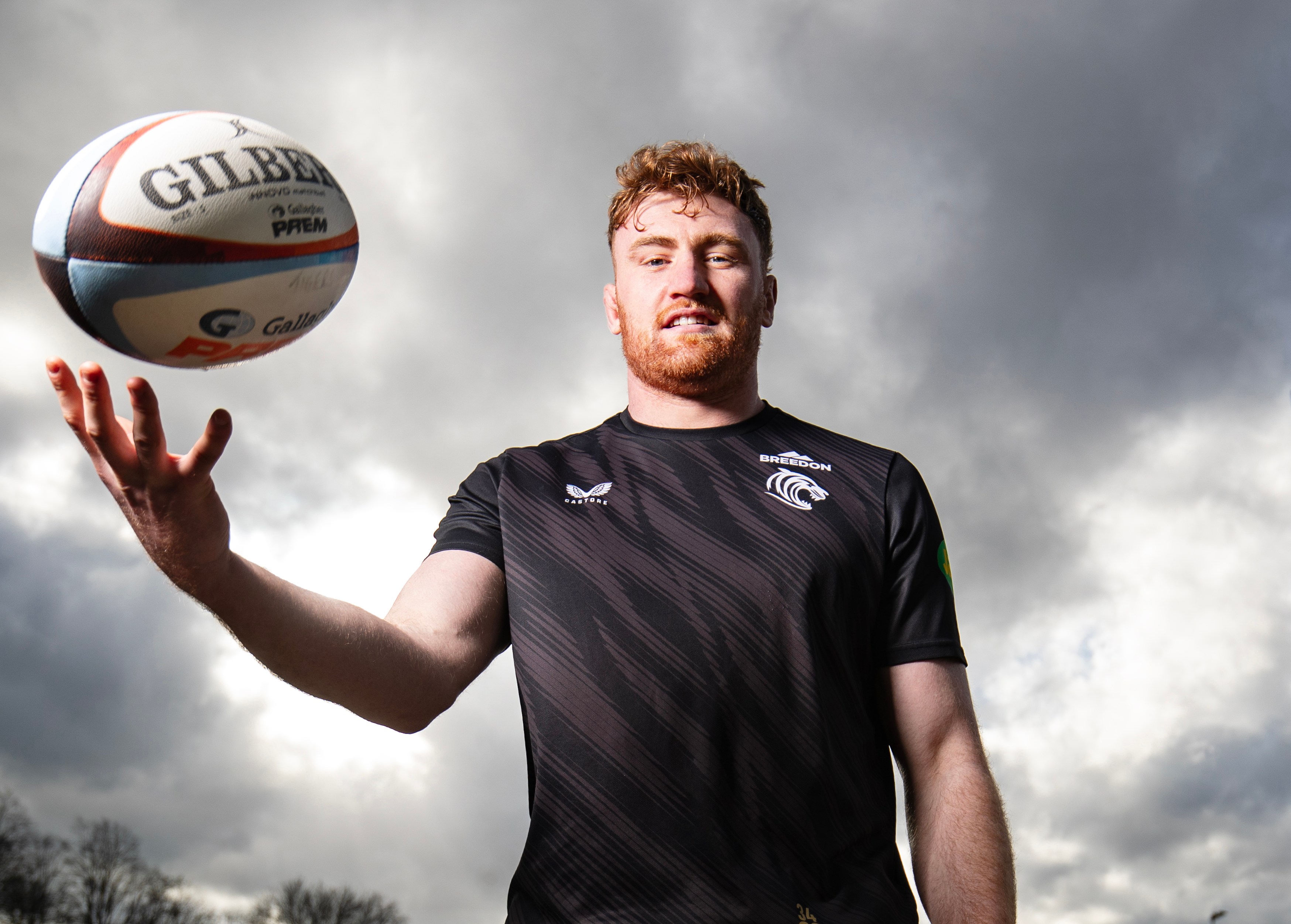Leicester Tigers captain, Ollie Chessum, at the club's training ground, tossing a rugby ball in the air.