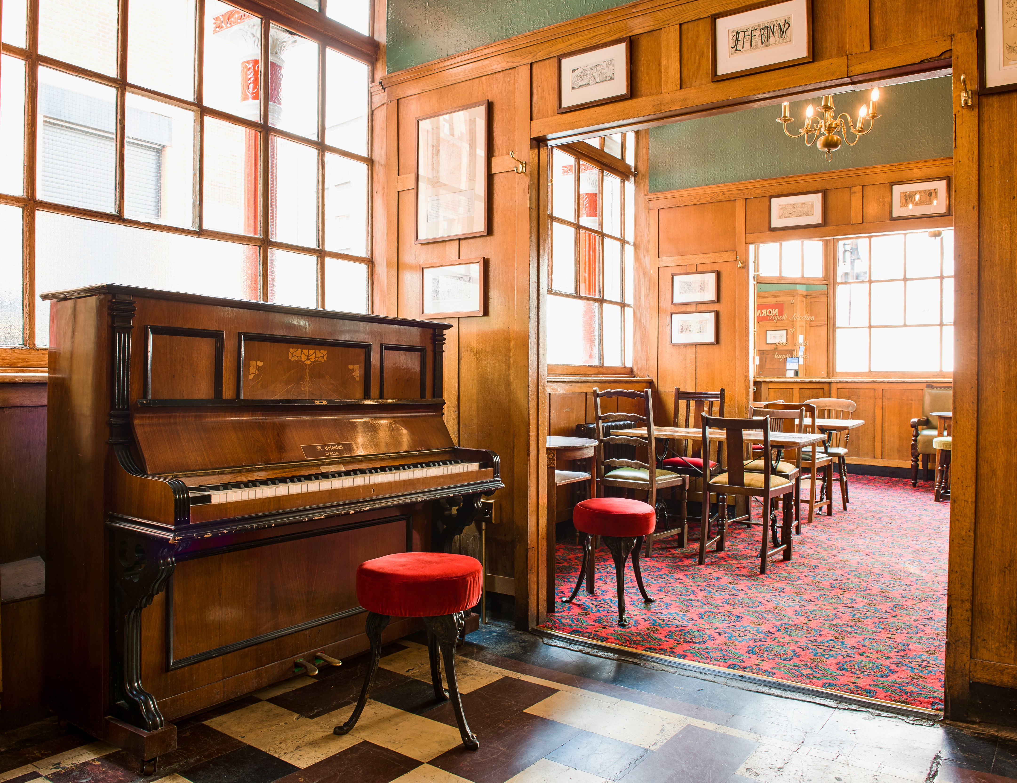 Interior of the Coach and Horses Soho pub, featuring a piano and red patterned carpet.
