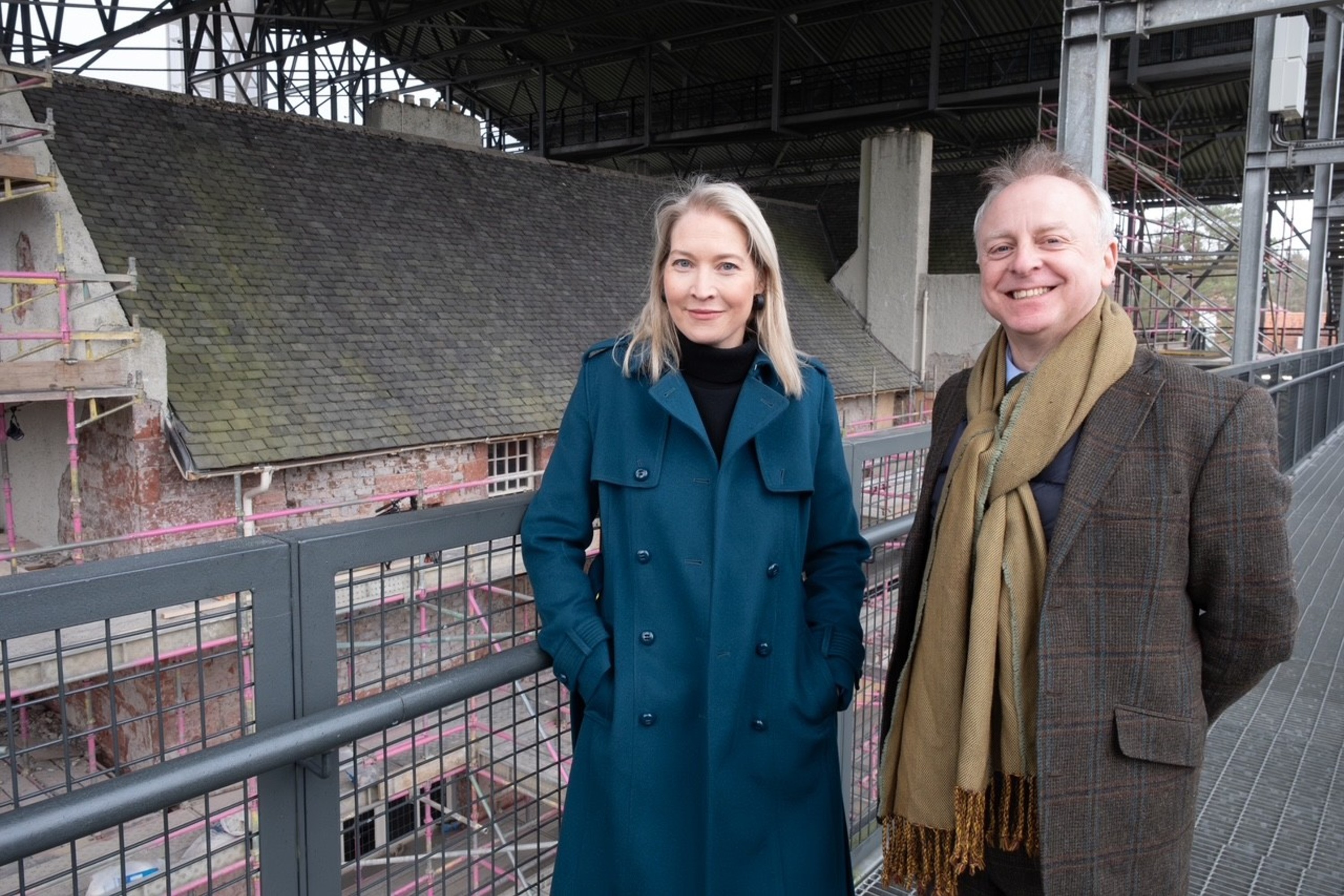 Caroline Clark and Phil Long smiling in front of the Hill House renovation site.