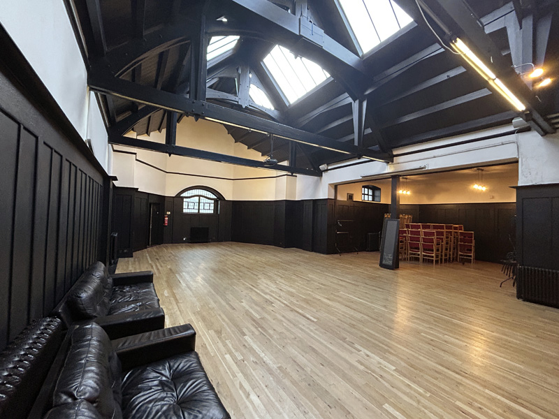 Interior of the Mackintosh Halls featuring wood paneling, light wooden floor, and exposed ceiling beams.