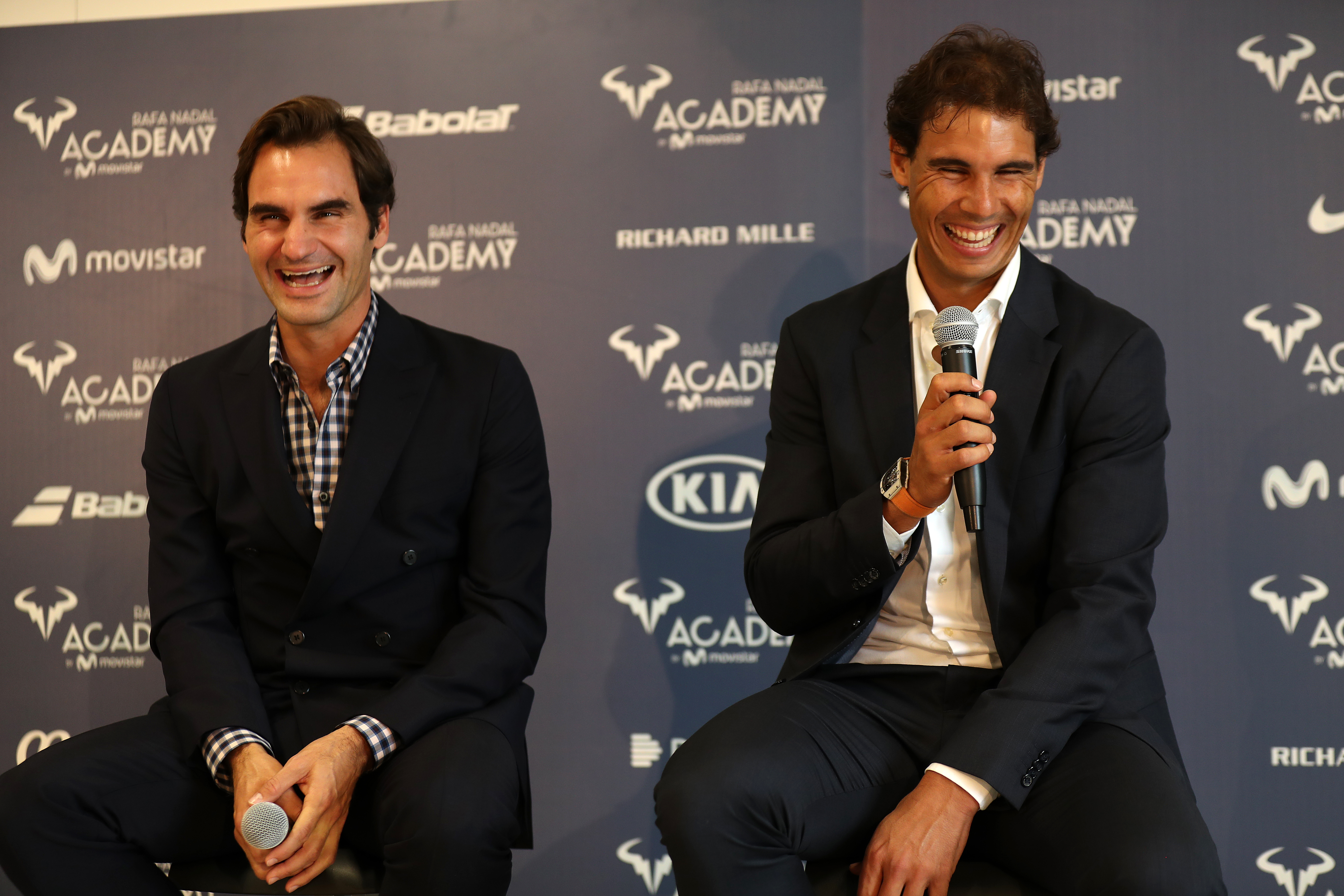 Roger Federer and Rafael Nadal sitting on stage at the opening of Nadal's tennis academy.