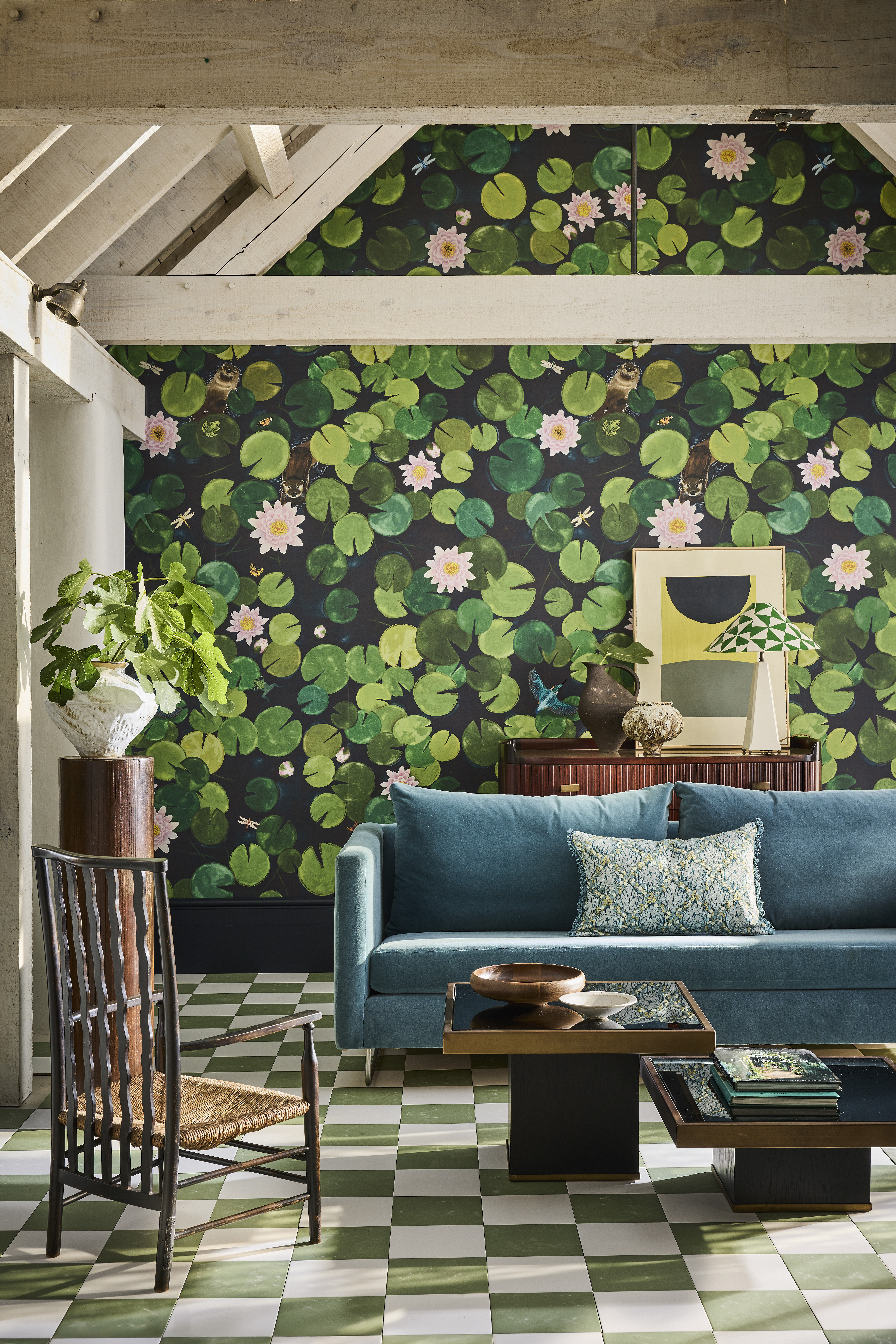 A living room with green and white checkerboard flooring, a teal sofa, and dark green wallpaper patterned with water lilies and otters.