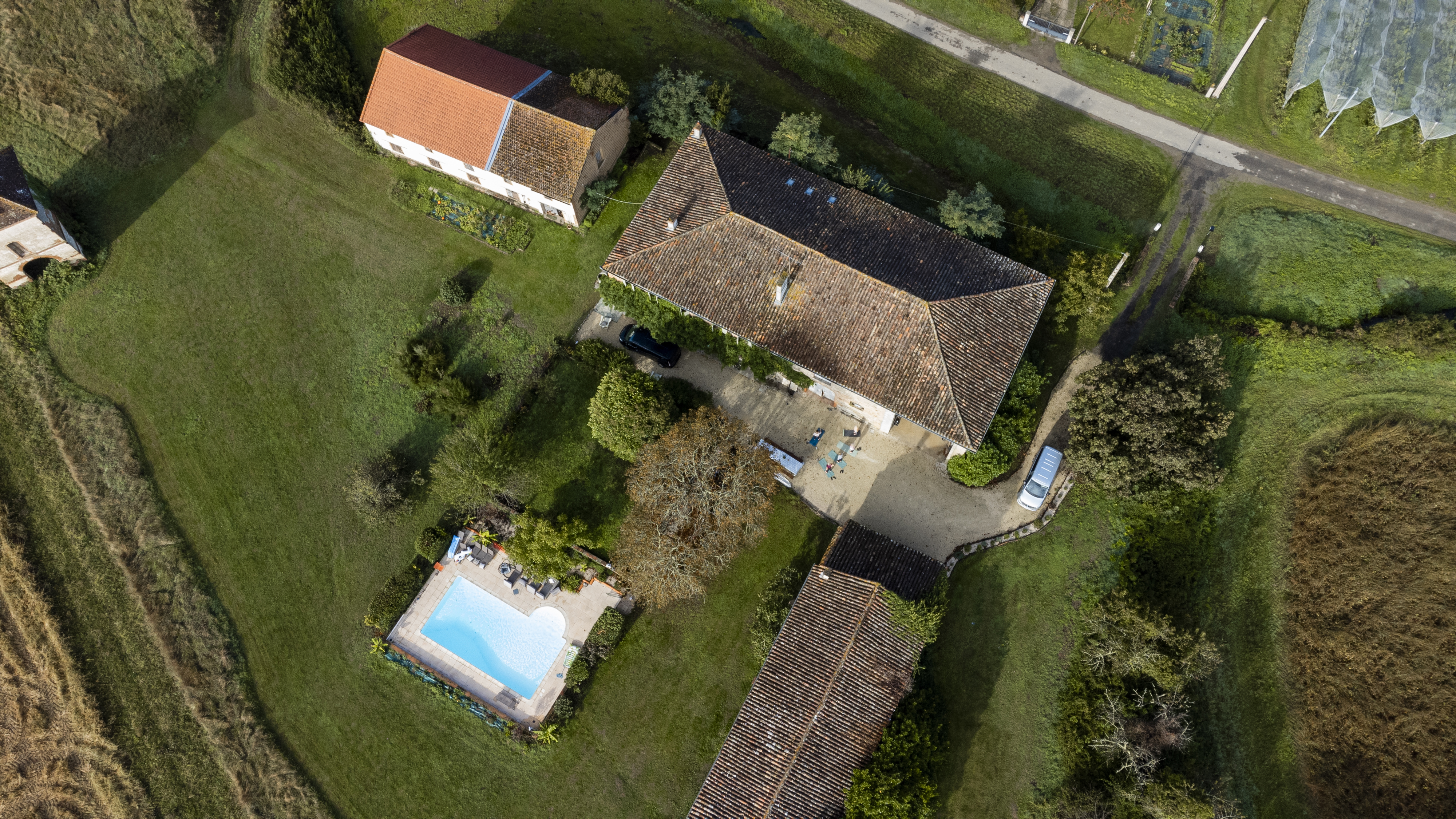 Aerial view of a vacation rental home in Castelferrus, France, showing three buildings and a swimming pool.