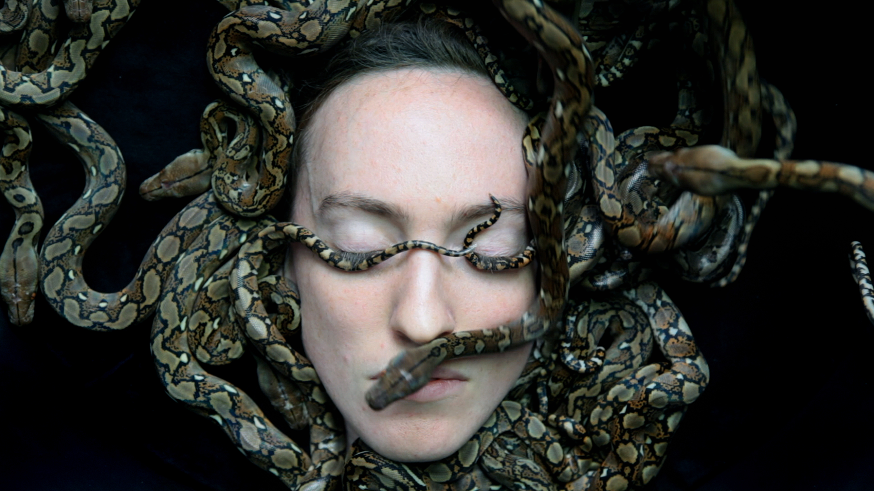 SPAWN by Juul Kraijer, featuring a person's face with eyes closed, covered by multiple snakes.