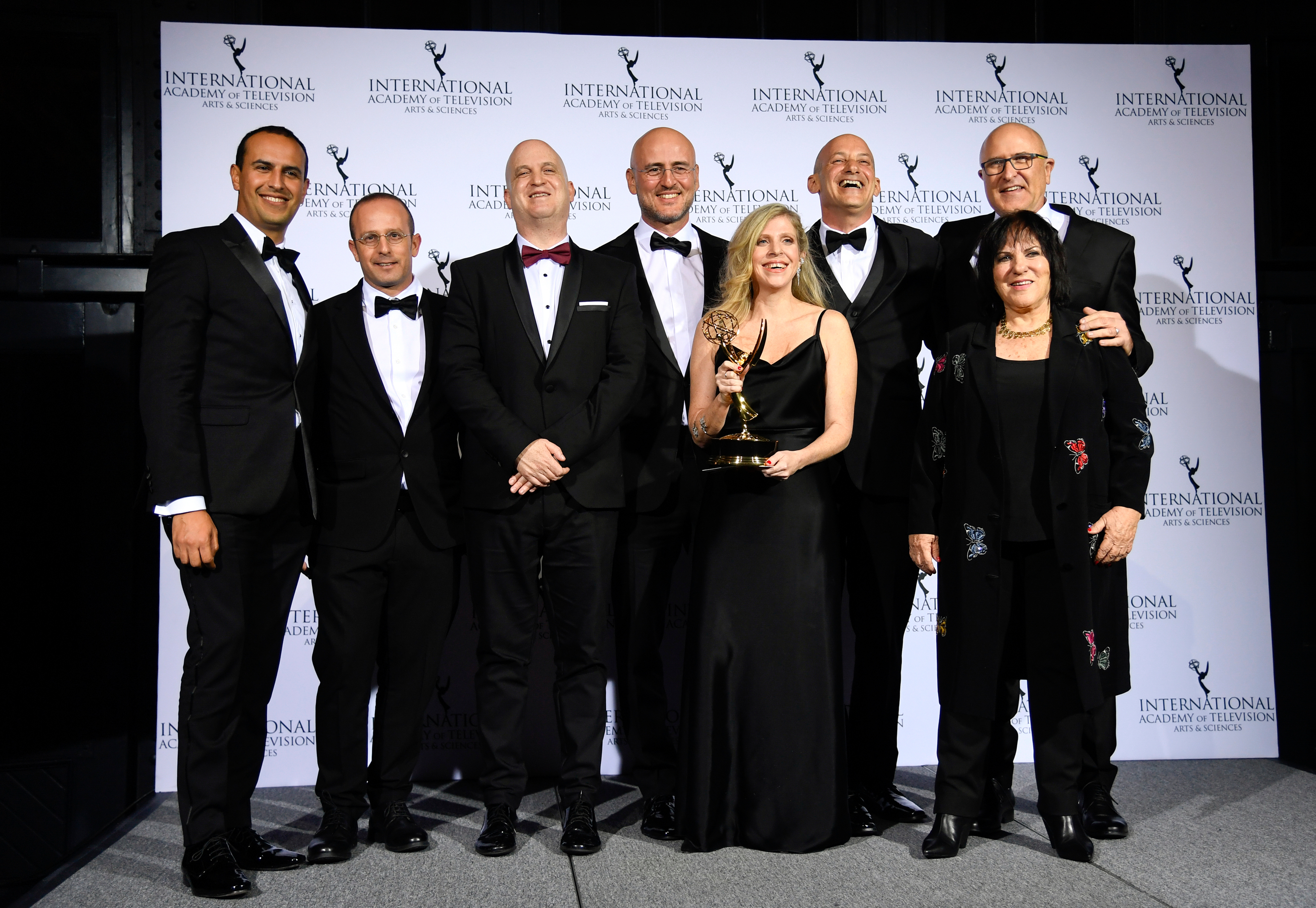 Producer Dana Eden holds the Emmy trophy as the "Tehran" team celebrates their award win.