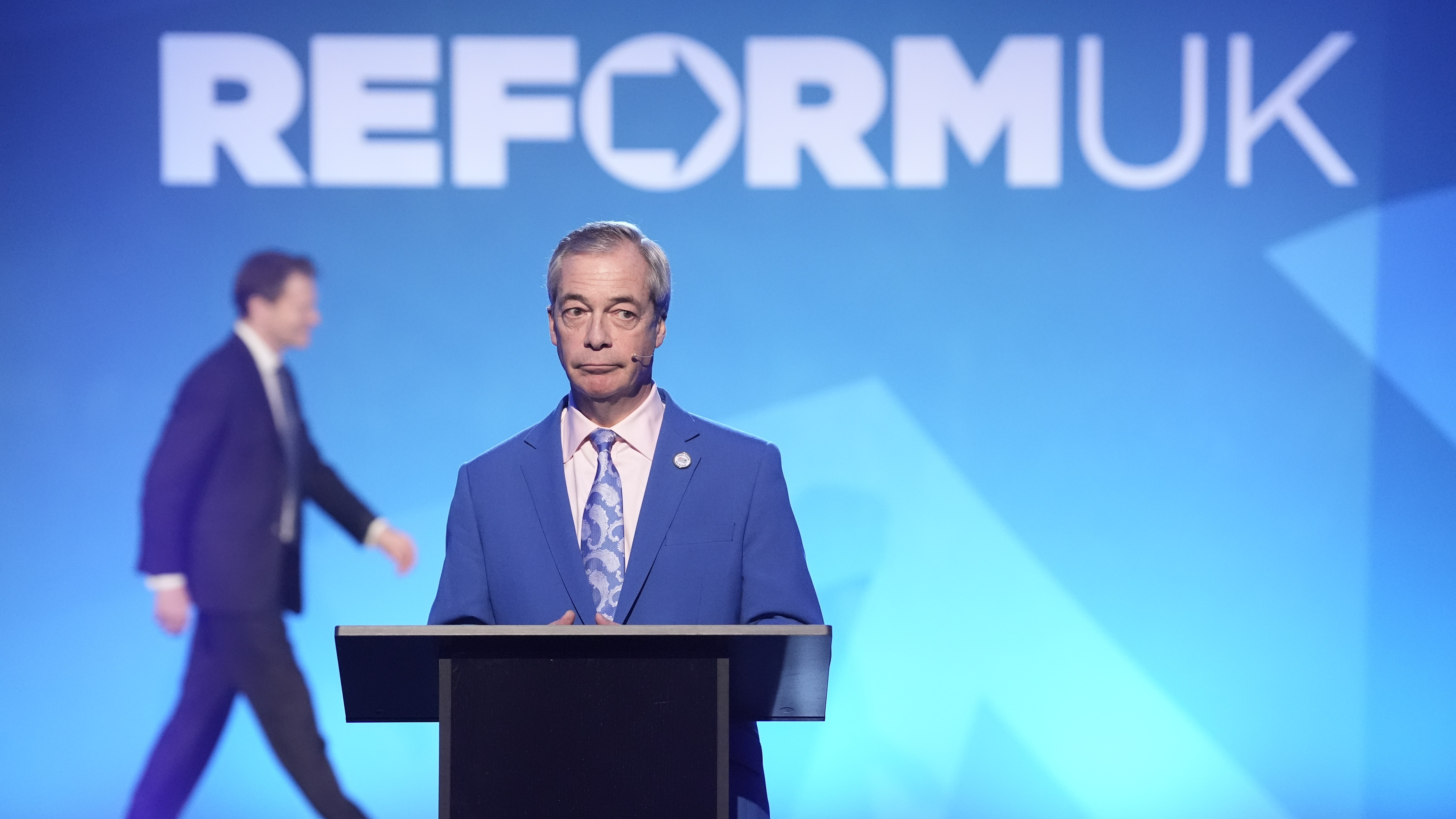 Nigel Farage at the conference in Church House, Westminster, with Jenrick in the background