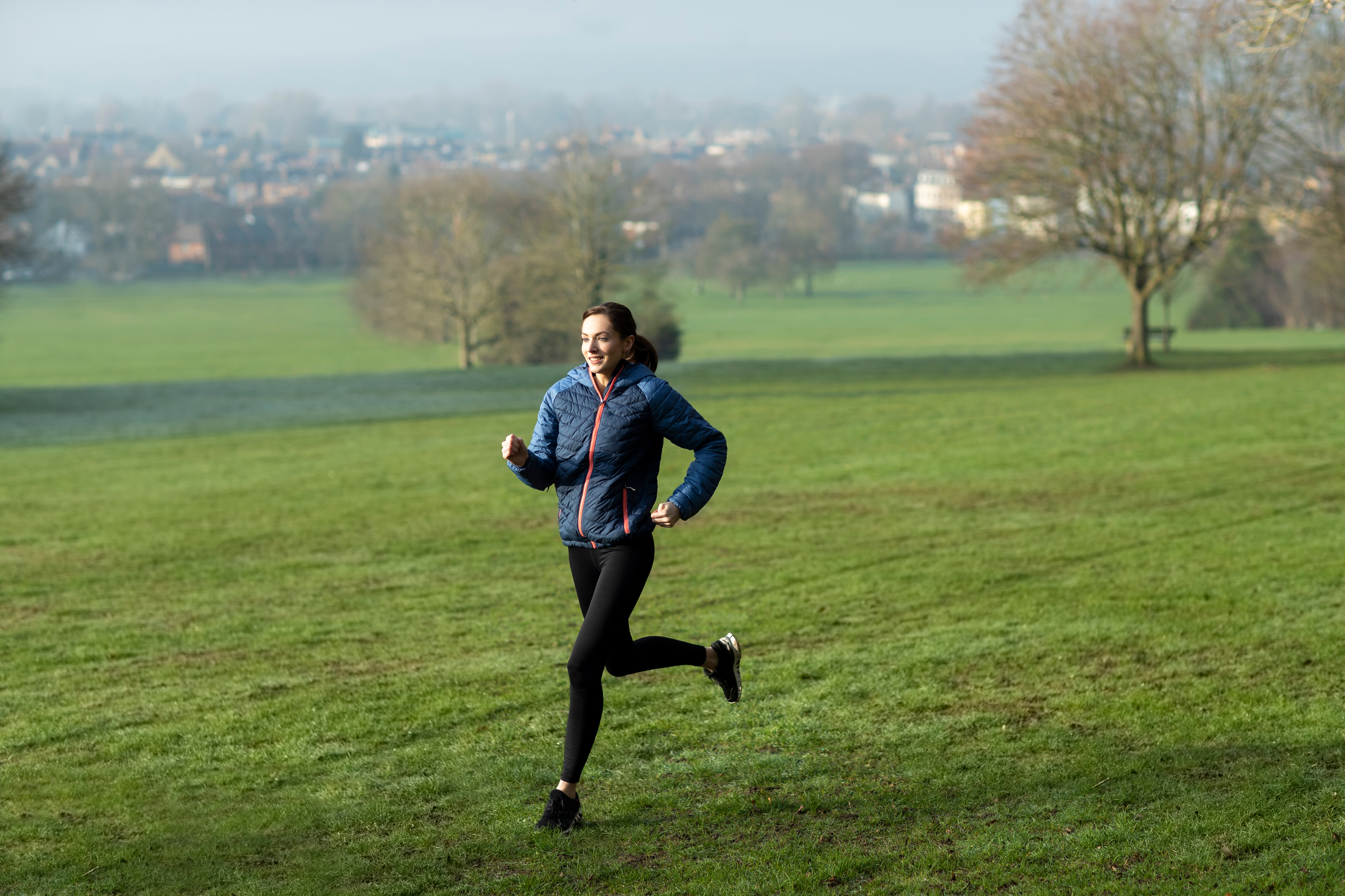 A young woman running in an autumn or winter park.