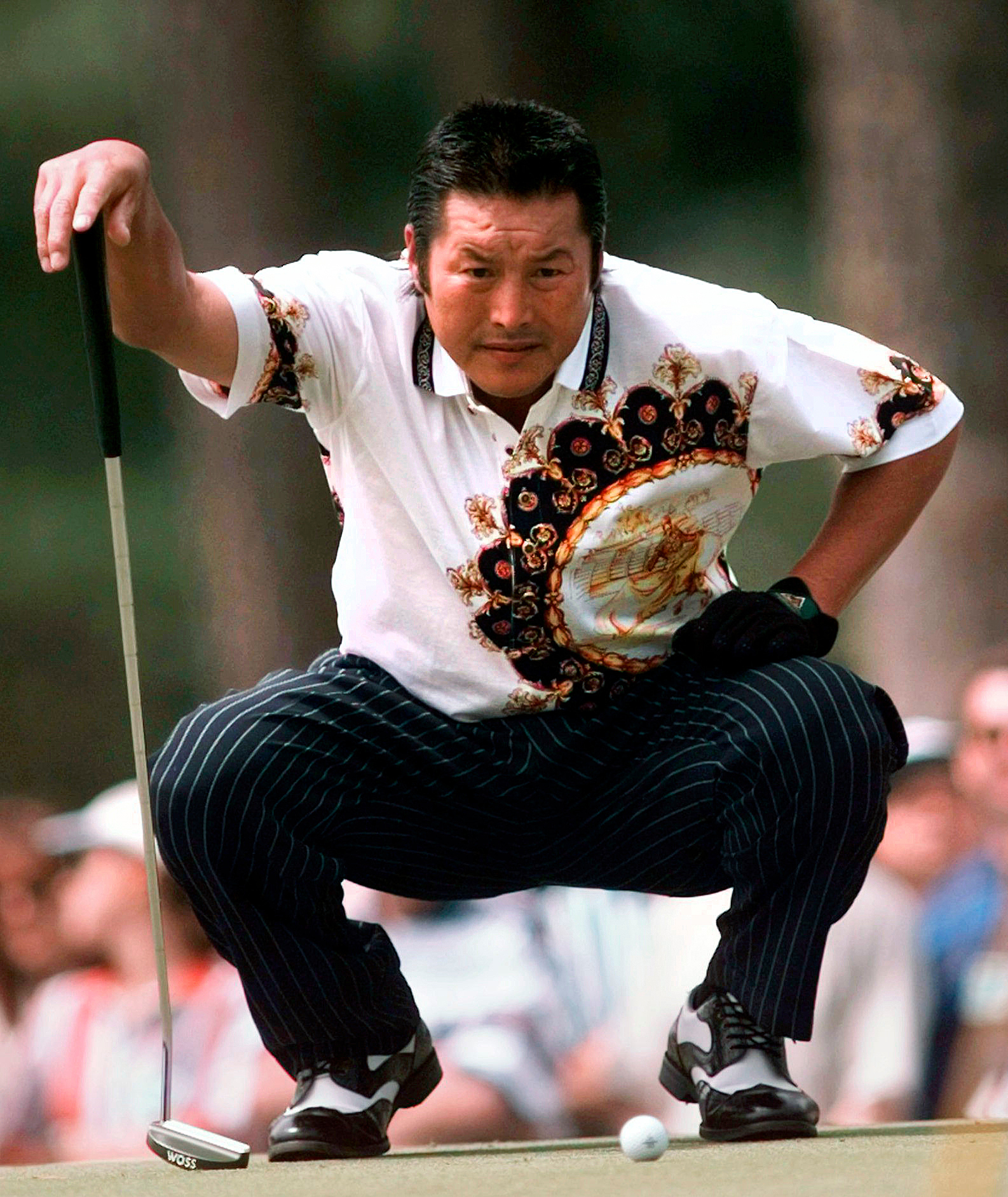 Golfer Jumbo Ozaki lining up a putt on the green.