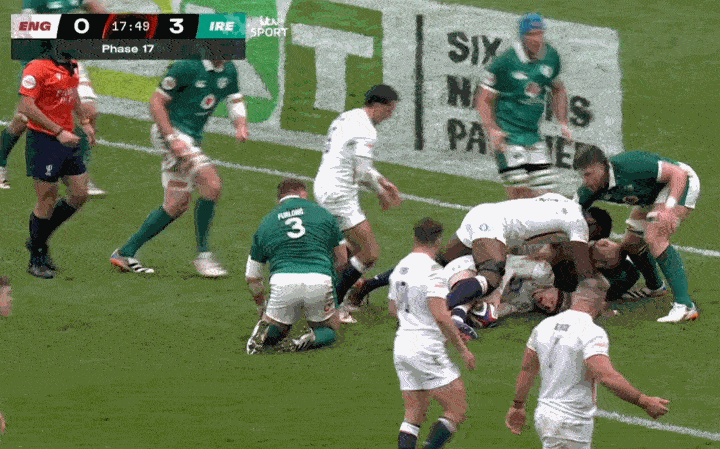Rugby players from England and Ireland in a ruck, with the score England 0, Ireland 3.