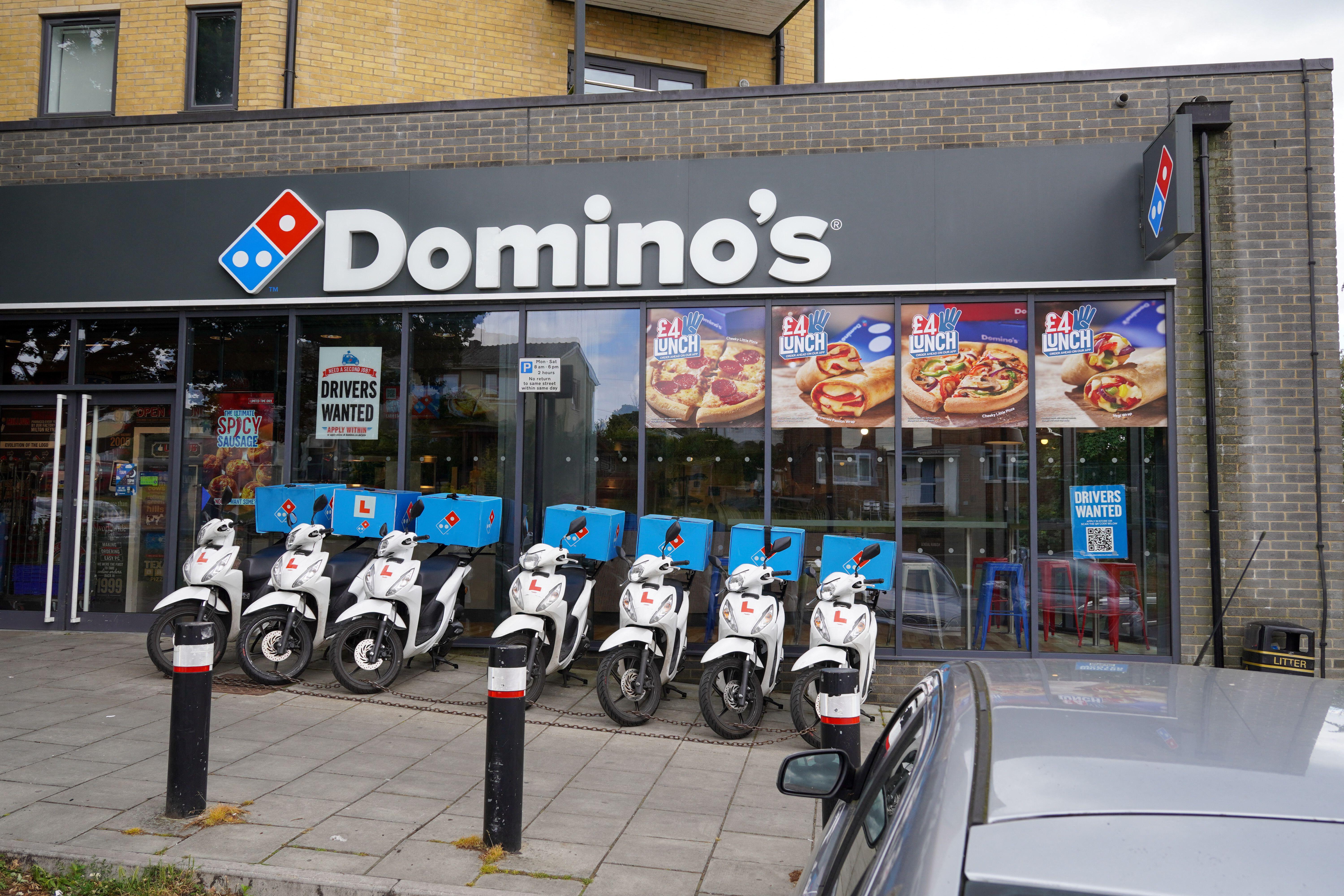 Domino's pizza takeaway restaurant entrance with delivery scooters parked outside.