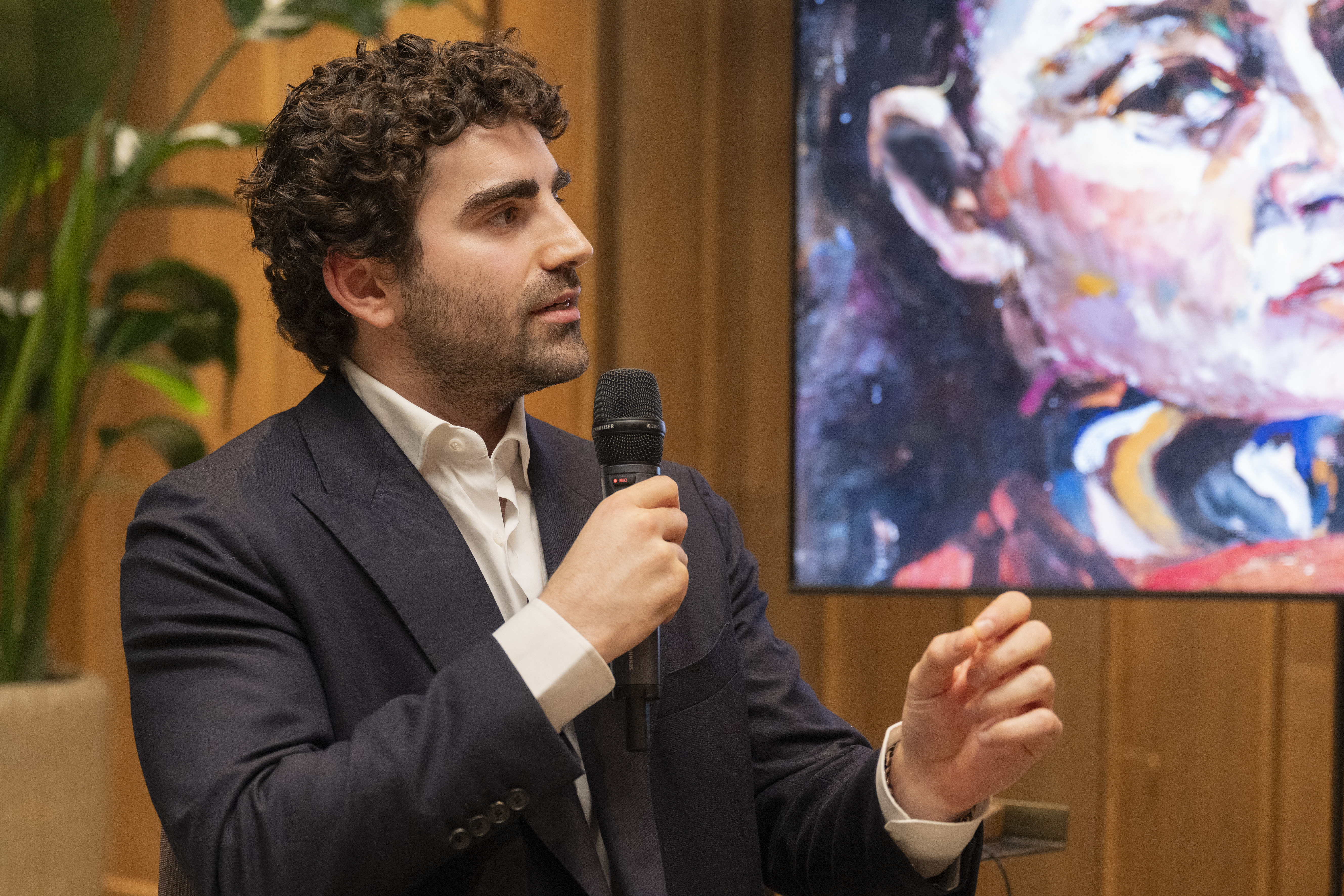 Matthew Perlman, curator of the Suzanne Perlman exhibition, speaking into a microphone.