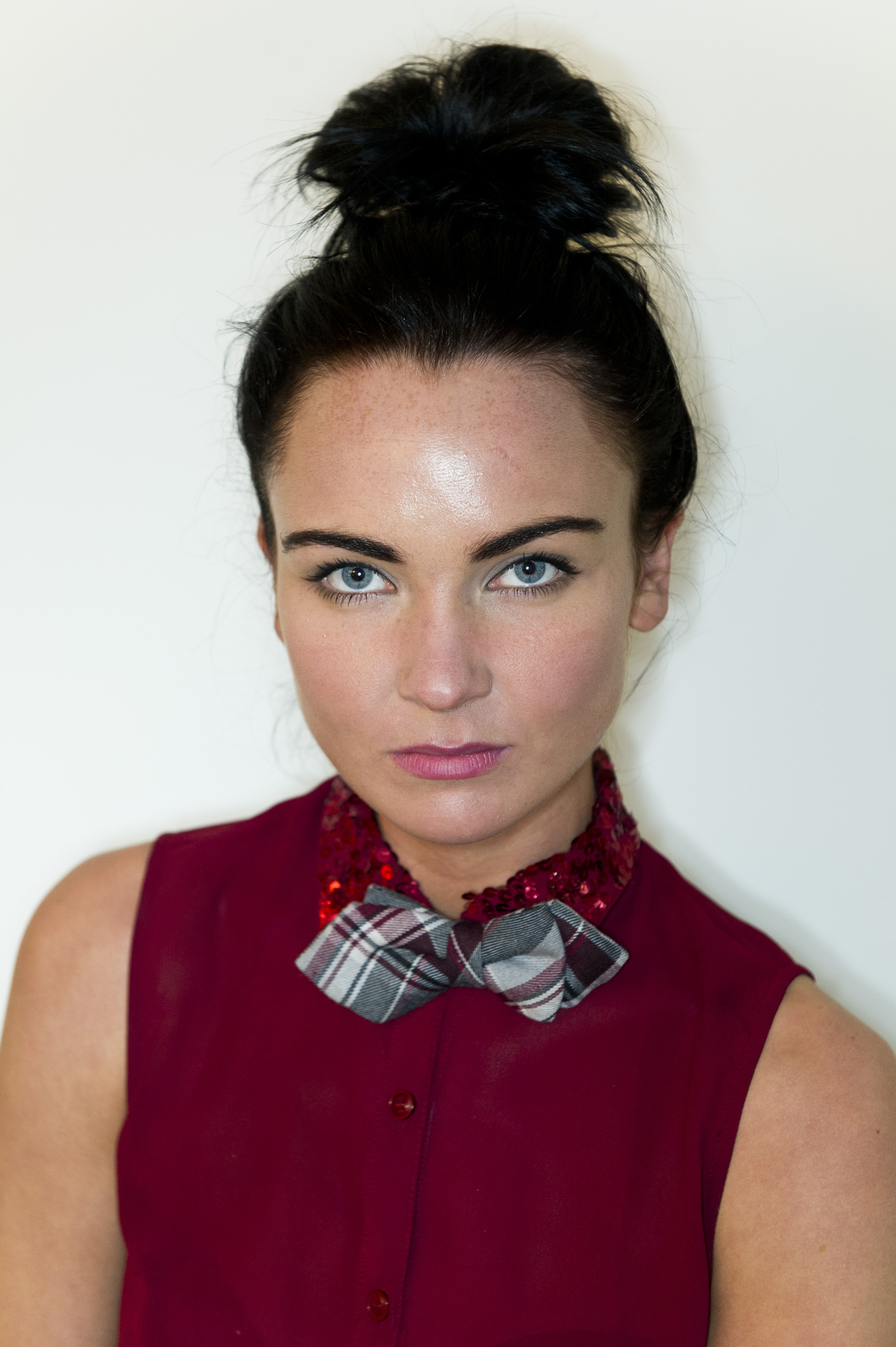 Model Diona Doherty wearing a red sleeveless shirt with a red sequined collar and a plaid bow tie.