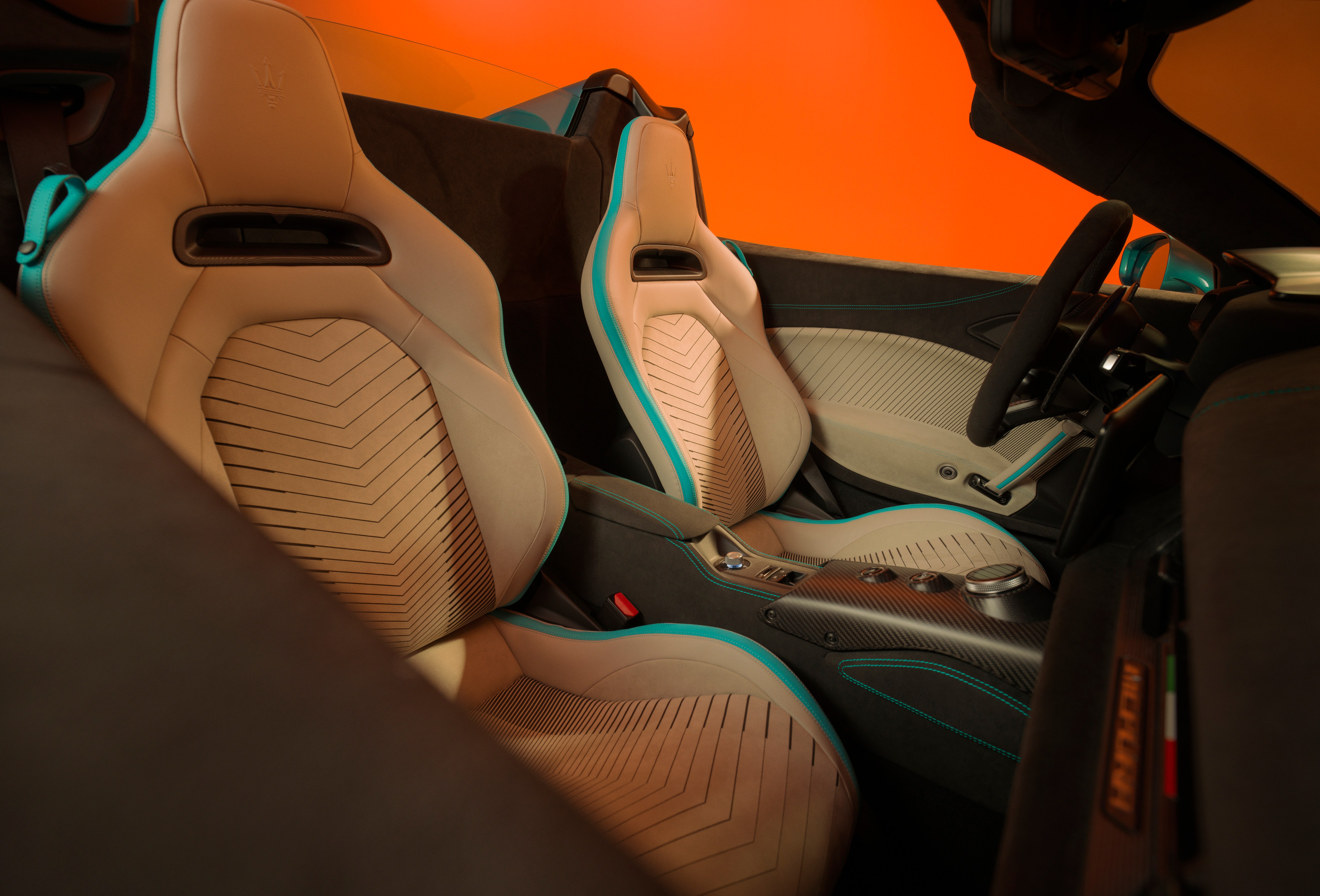 The interior of a Maserati MC20 Cielo with light-colored seats accented with turquoise trim and stitching.