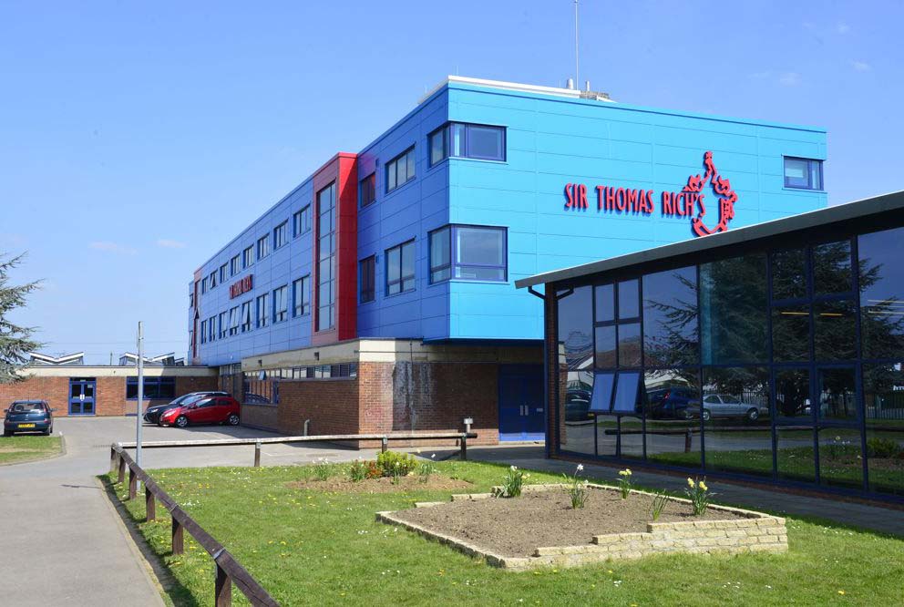 Sir Thomas Rich's School building with "Sir Thomas Rich's" sign in red on a bright blue wall.