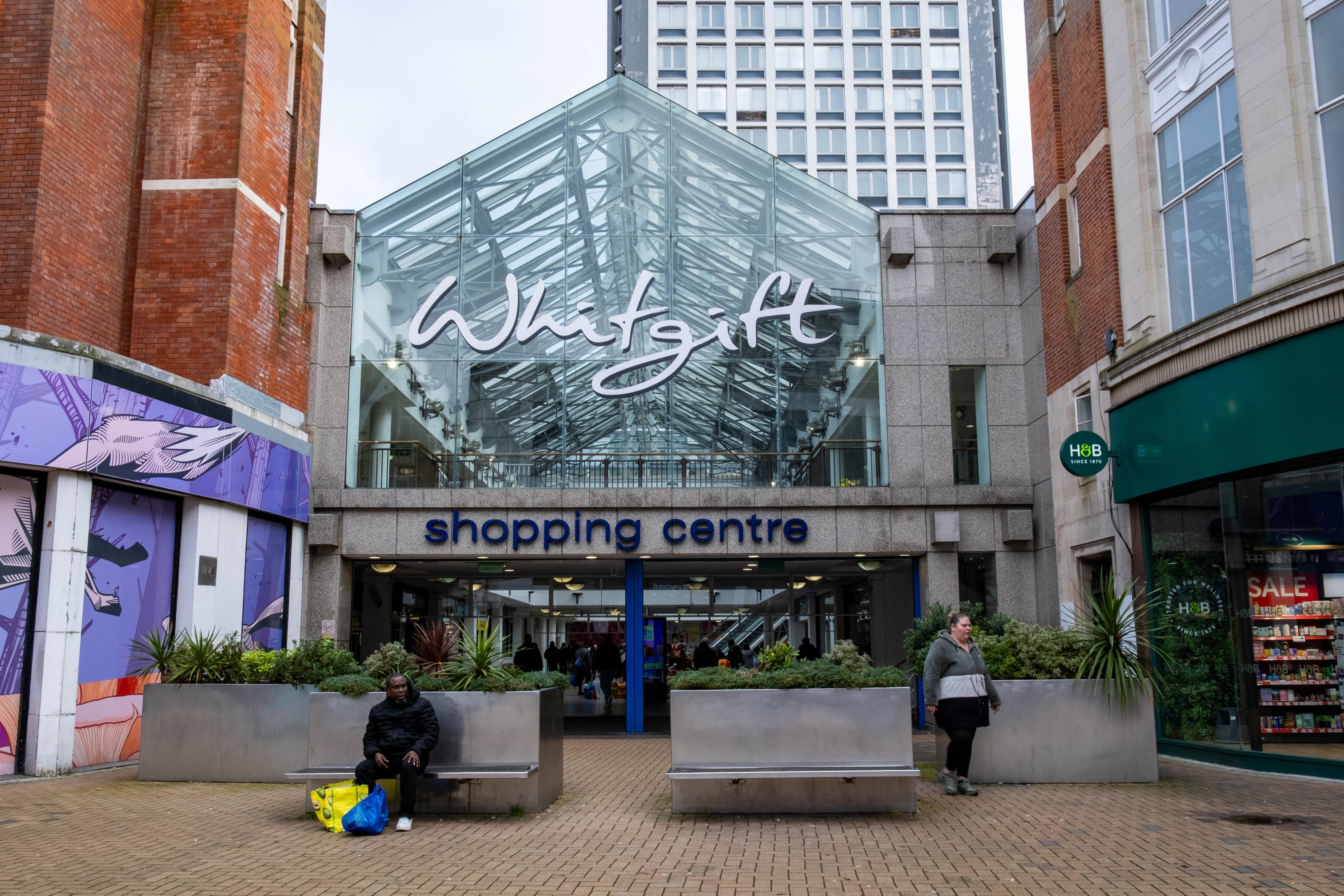 Exterior view of the Whitgift Shopping Centre in Croydon, with a large glass facade and a sign reading "Whitgift shopping centre."