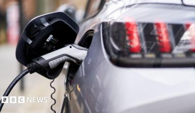 Close-up of an electric car charger plugged into a silver car
