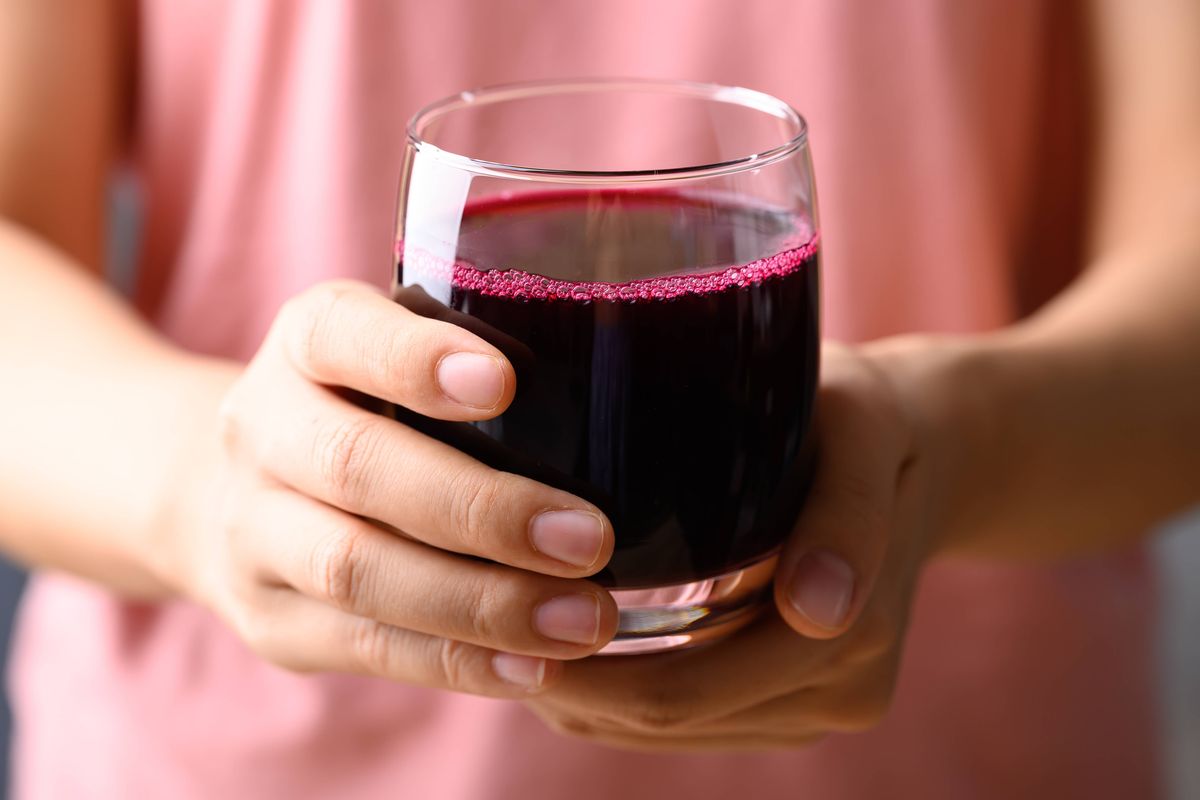 Fresh beetroot juice in glass holding by woman hand, Healthy drink