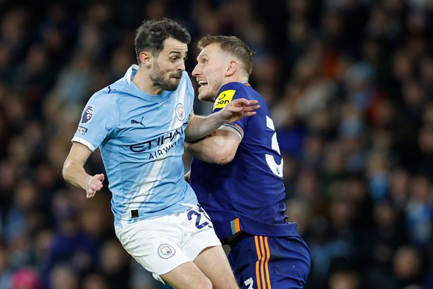 Bernardo Silva of Manchester City challenges Dan Burn of Newcastle United