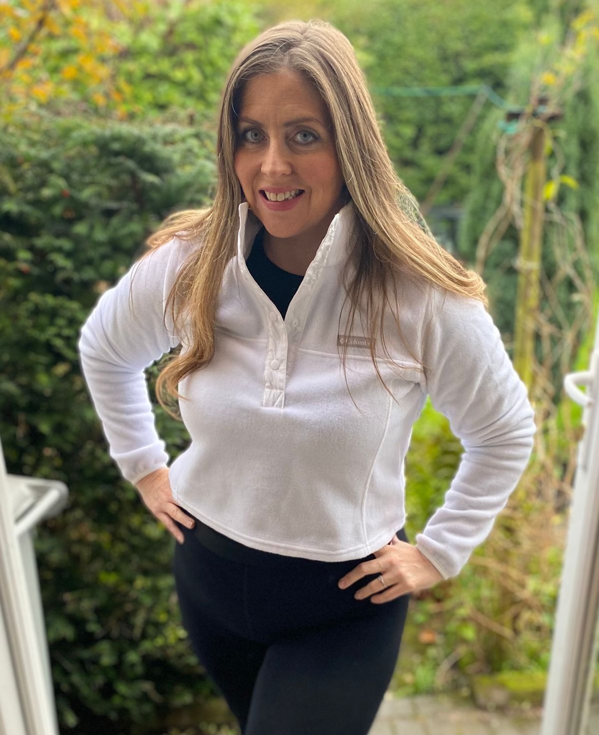 Woman in black leggings and white button top posing for a picture