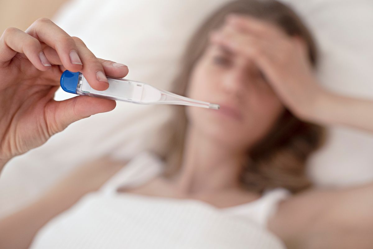 Young woman taking her temperature.