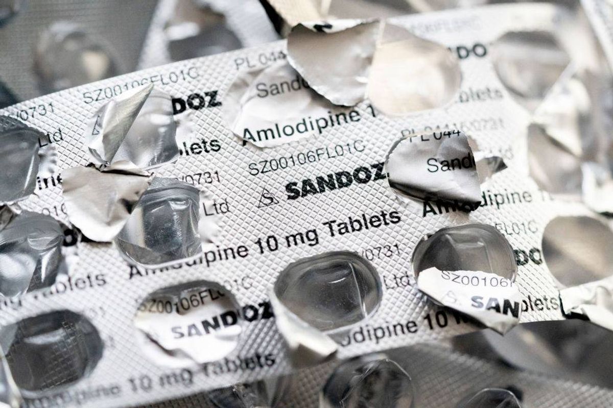A close-up view of multiple blister packs of medication, some of which are torn, displaying various labels with text and numbers, including the name "Sandoz."