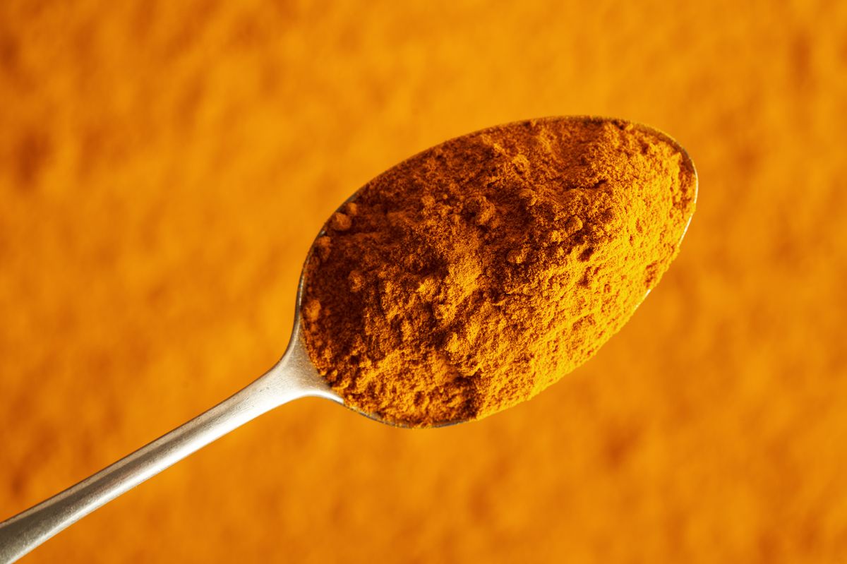Turmeric root powder on a metal spoon, top view