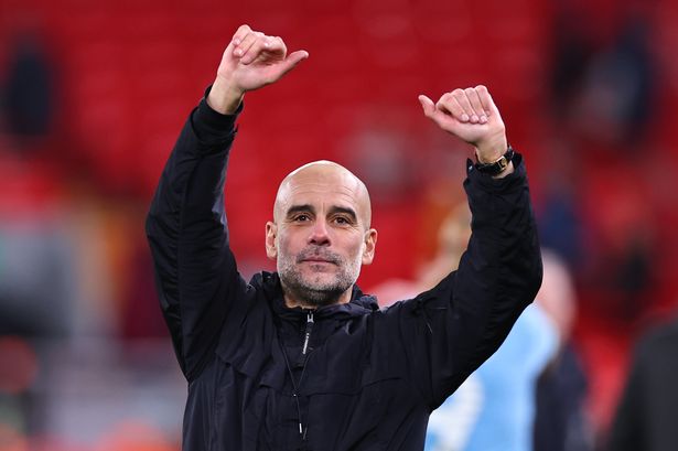 Pep Guardiola raises his arms in celebration.