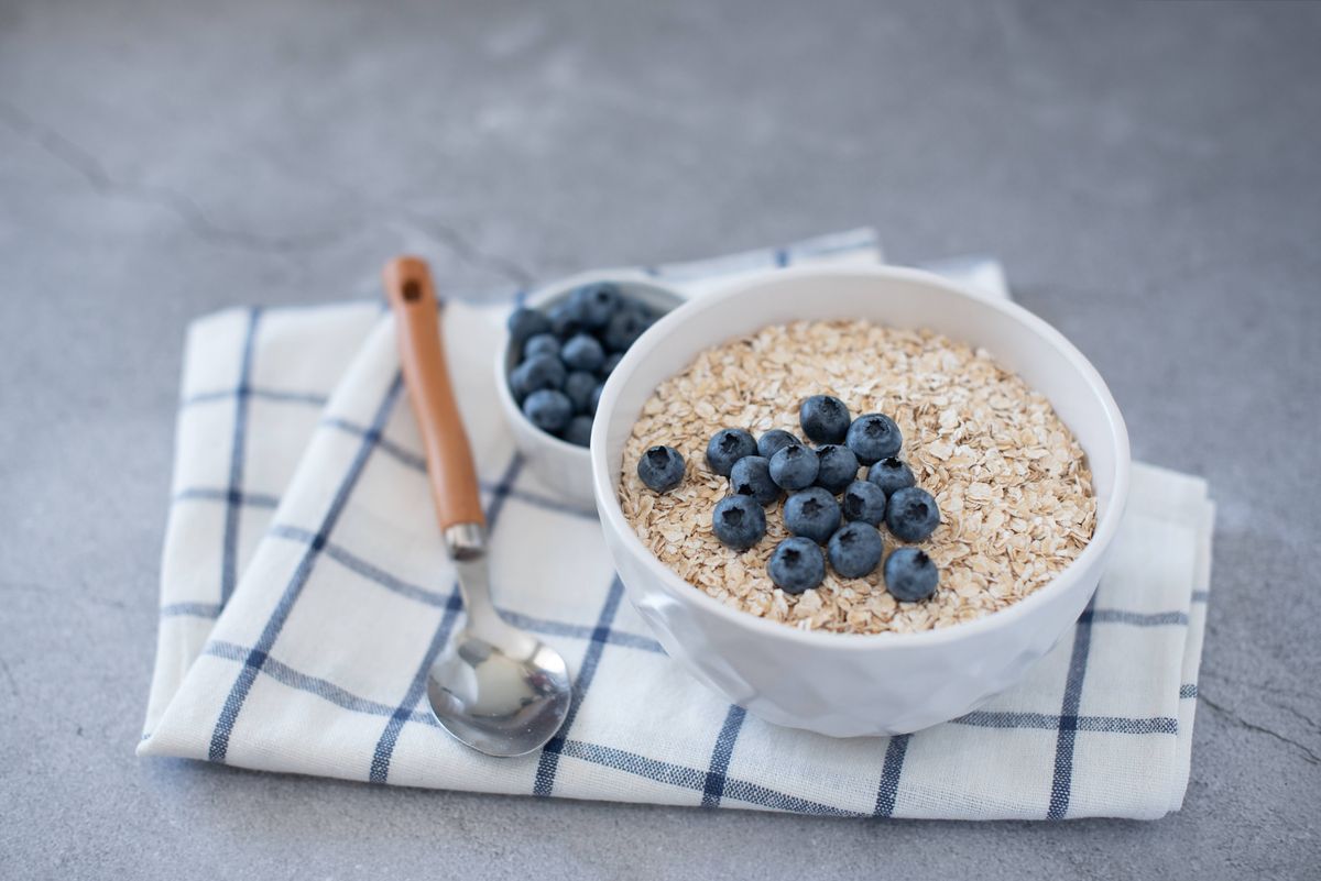 Homemade oatmeal with blueberries and strawberries in bowl on gray concrete background. Healthy breakfast