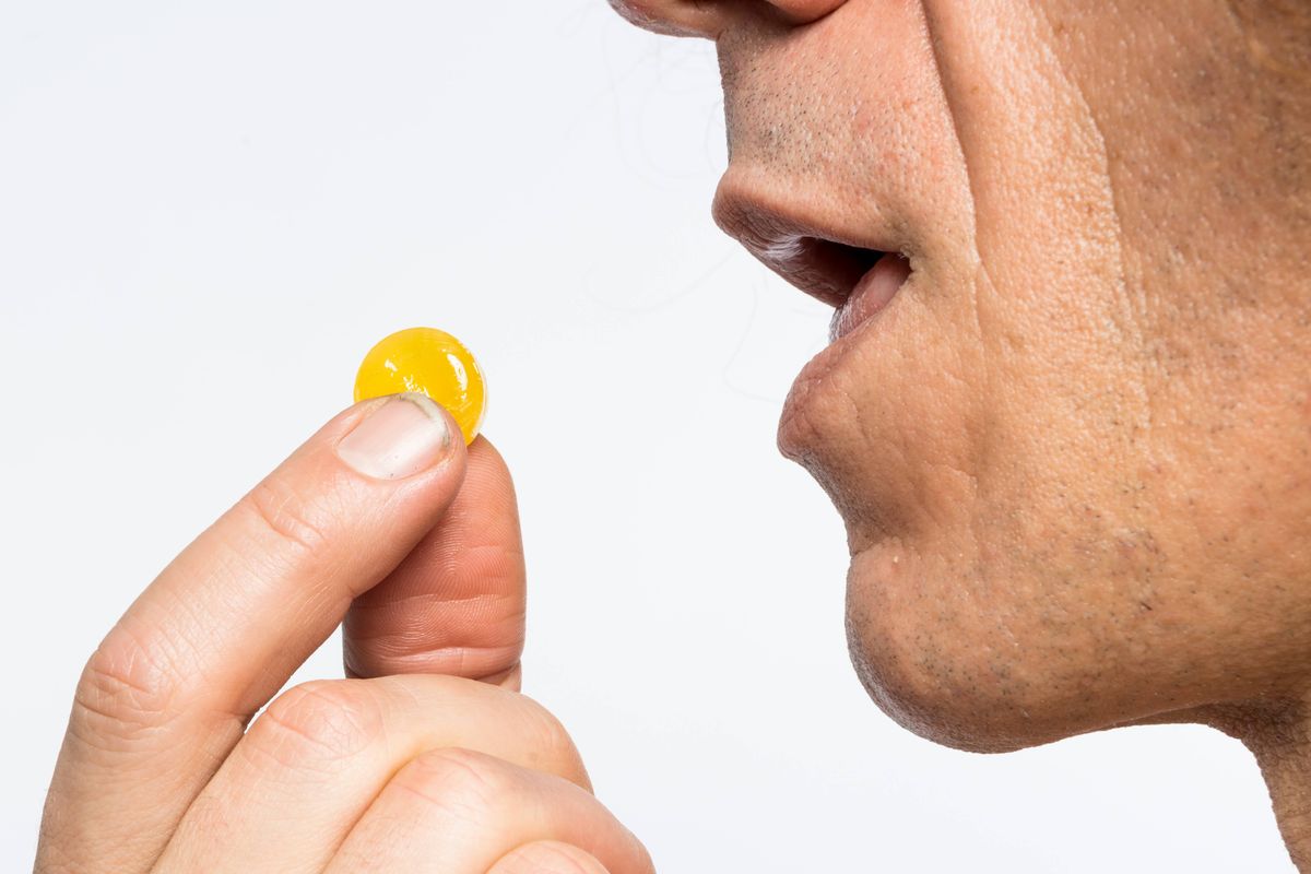 Cropped shot of bare chested mediterranean man taking colourful pill