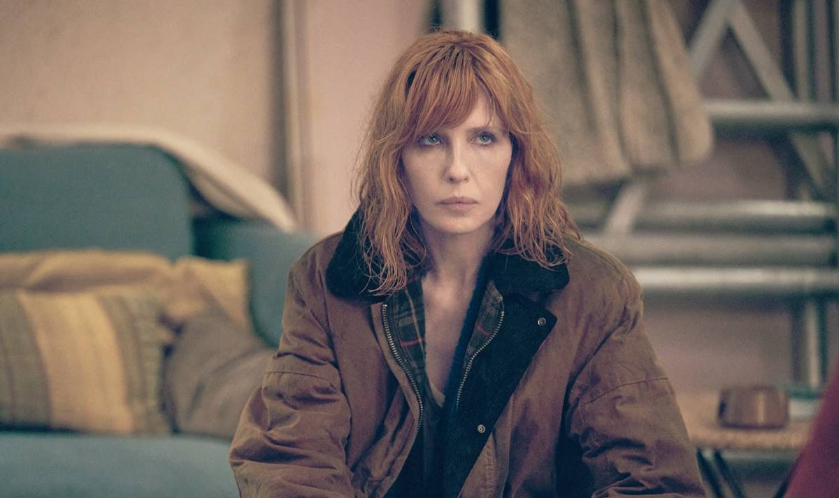 A woman sits in a lounge and looks serious