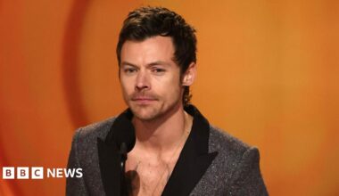 Harry Styles at the Grammys wearing a sparkly grey jacket and black collar