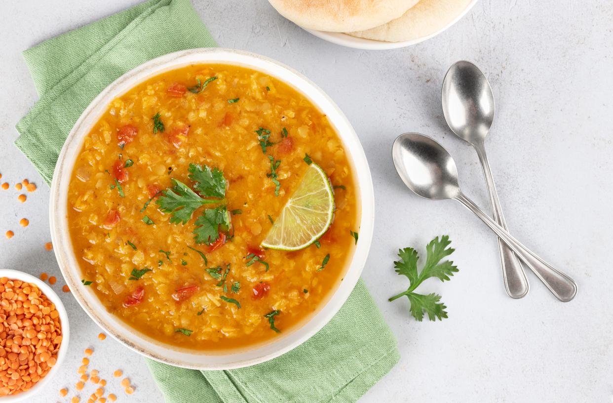 Traditional Indian dal soup with red lentils, spices, fresh cilantro and lime on a white background. Indian food. High quality photo