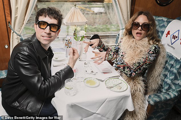 Nick wore a black leather jacket and dark blue jeans as we;; as a pair of orange tinted glasses as he enjoyed the train ride