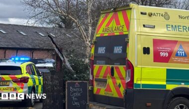 An ambulance and ambulance response vehicle are parked at the farm. A sign says 'bouncy castle this way' while another says 'parking this way'.