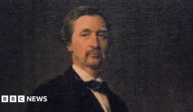 Portait of a young Lord Henry Stanley, who has short fair hair and moustache. He wears a tie or cravat with his suit. It is on a black background.