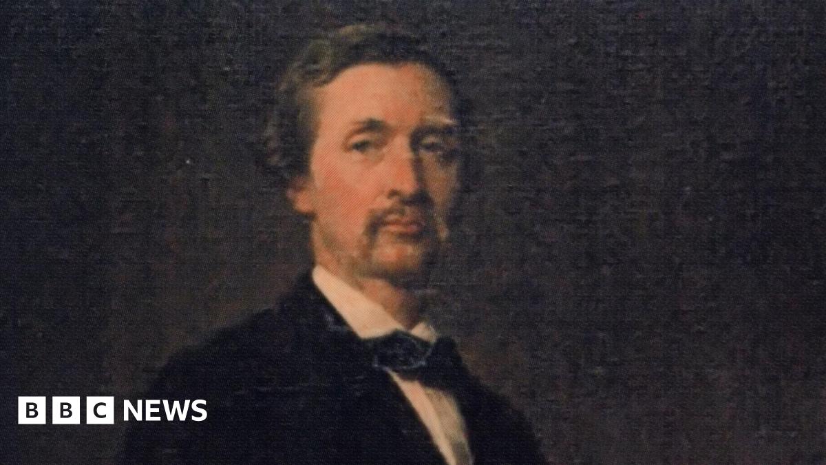 Portait of a young Lord Henry Stanley, who has short fair hair and moustache. He wears a tie or cravat with his suit. It is on a black background.