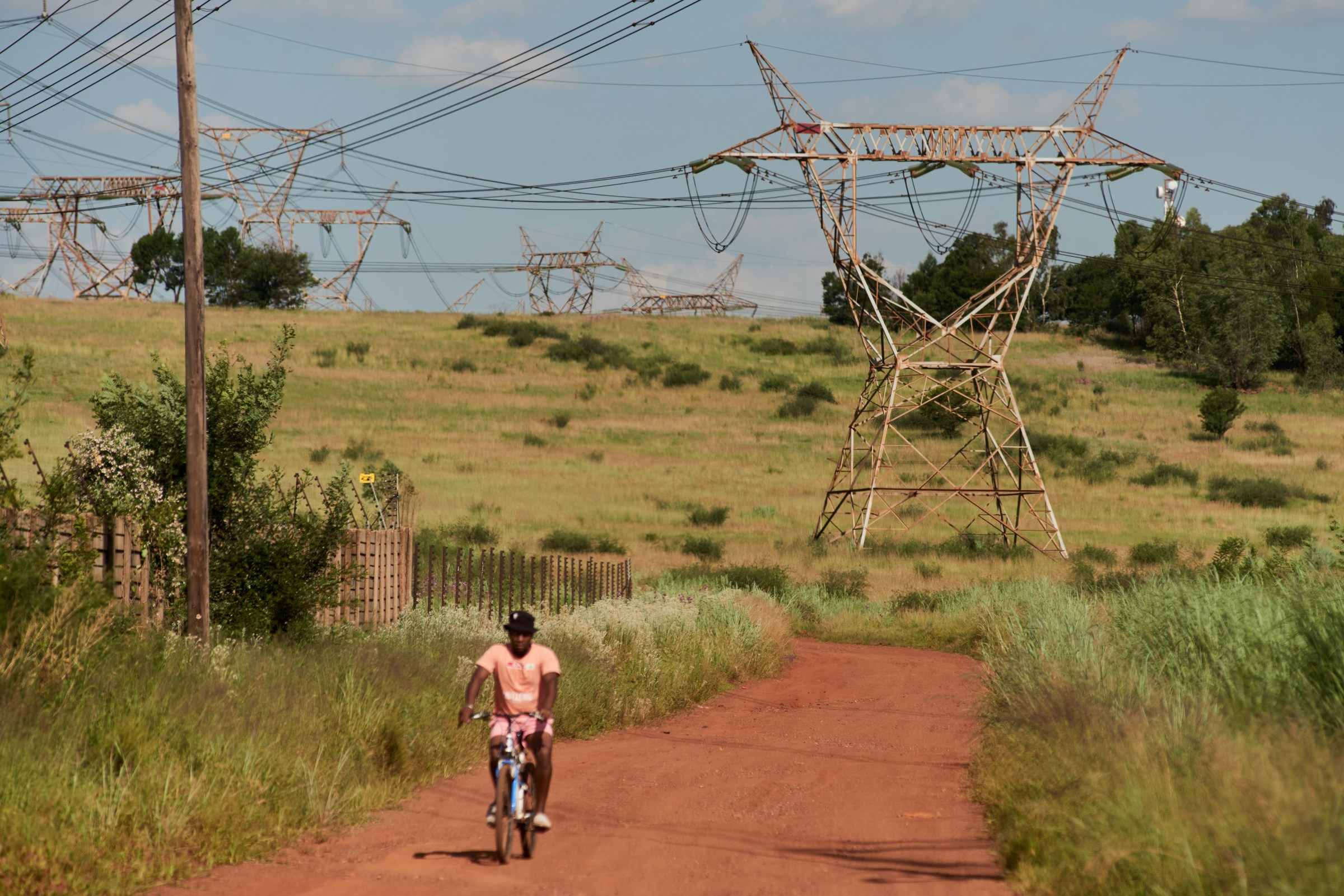 A man cycling past power lines in South Africa
