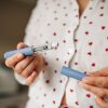 A woman in pajamas is shown holding an injection pen in front of her torso.