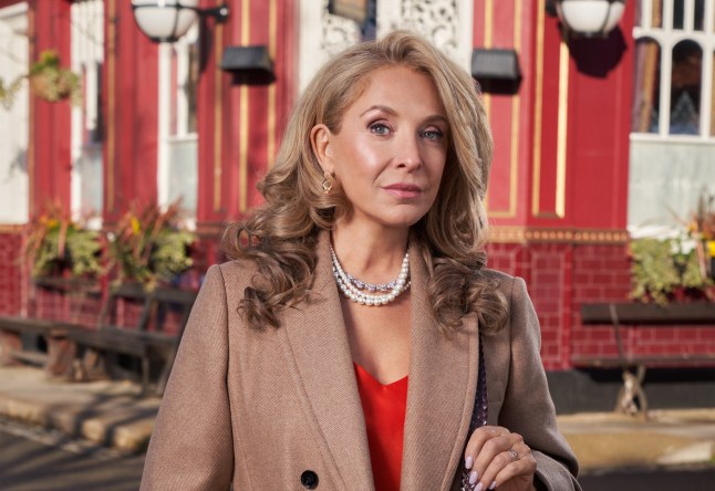 Chrissie Watts looking serious in front of the Queen Vic pub in EastEnders.