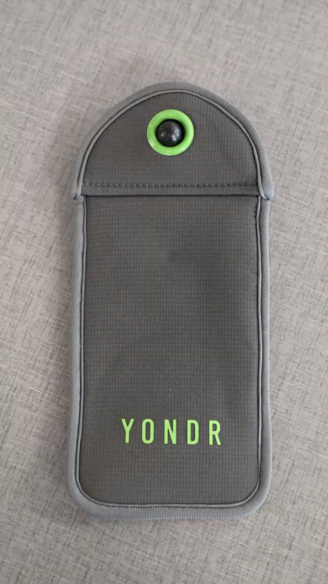 This photo shows a Yondr pouch. It's gray and shaped roughly like a cellphone, with a curved opening at the top.
