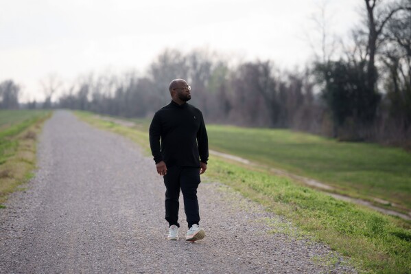 Gary C. Watson, Jr., who was born and raised in St. John the Baptist Parish, walks on a path in Edgard, La., Wednesday, Feb. 18, 2026, across the river from a Marathon Petroleum Refinery. (AP Photo/Matthew Hinton)