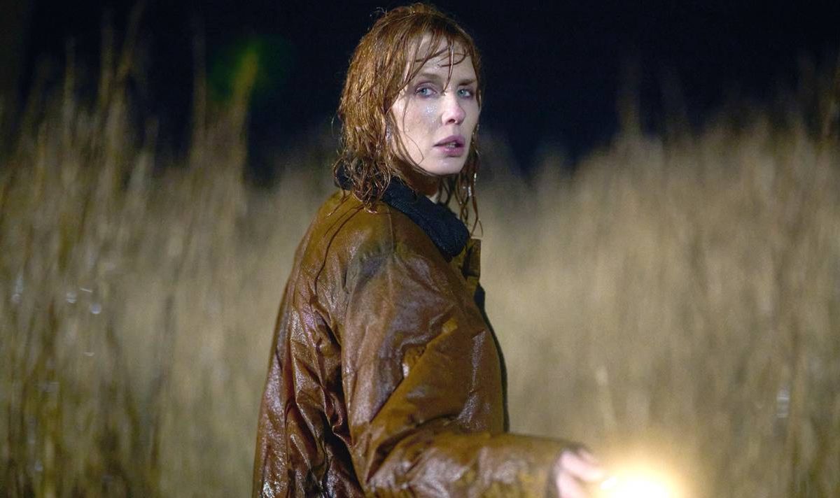A drenched woman holds a torch in the rain