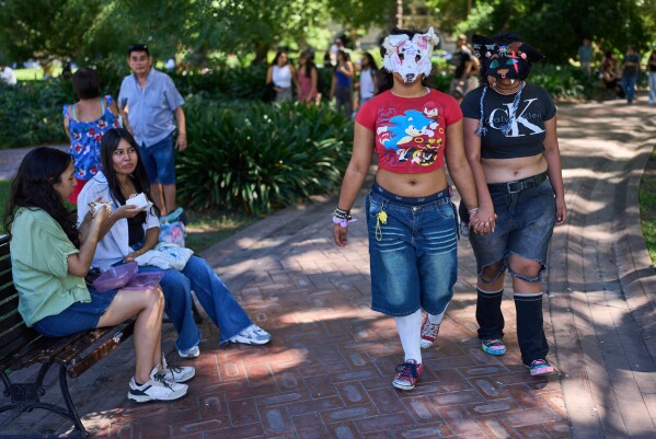 Youths walk through a park during a gathering of therians, people who say they identify as non-human animals, in Buenos Aires, Argentina, Sunday, Feb. 22, 2026. (AP Photo/Rodrigo Abd)