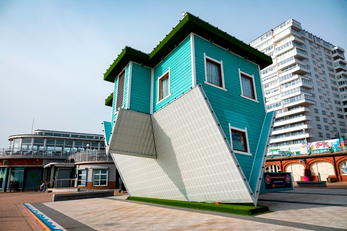 The image shows a bright blue small house which is upside down