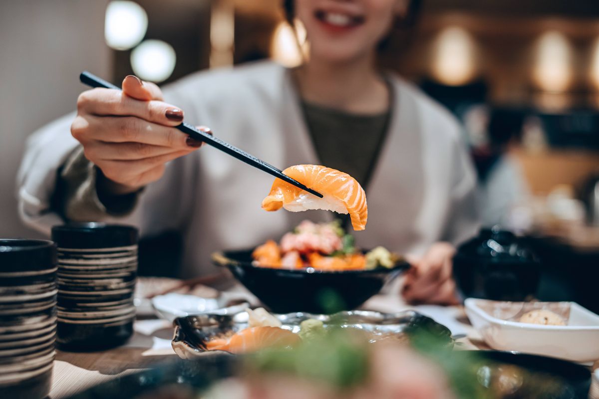 Woman enjoying delicate freshly served sushi with chopsticks