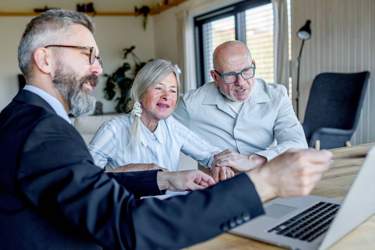 Elderly couple talking with financial advisor about budget and investments.