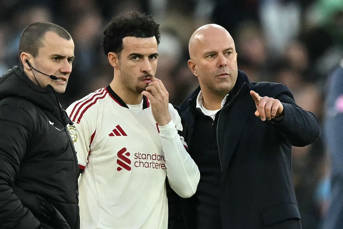 Liverpool's Dutch manager Arne Slot (R) speaks with Liverpool's English midfielder #17 Curtis Jones (C) as he prepares to come on as a substitute during the English Premier League football match between West Ham United and Liverpool at the London Stadium, in London on November 30, 2025. (Photo by Ben STANSALL / AFP via Getty Images) / RESTRICTED TO EDITORIAL USE. No use with unauthorized audio, video, data, fixture lists, club/league logos or 'live' services. Online in-match use limited to 120 images. An additional 40 images may be used in extra time. No video emulation. Social media in-match use limited to 120 images. An additional 40 images may be used in extra time. No use in betting publications, games or single club/league/player publications. /