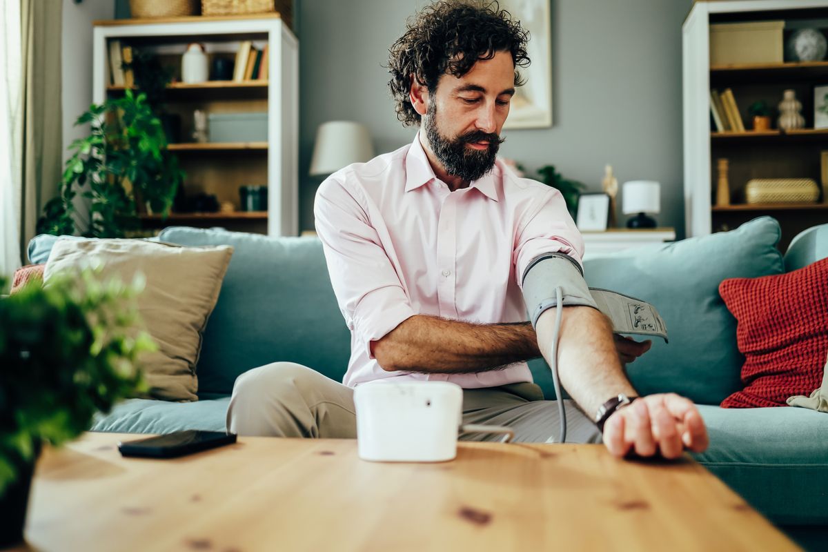 Man checking his blood pressure with a medical device in a living room